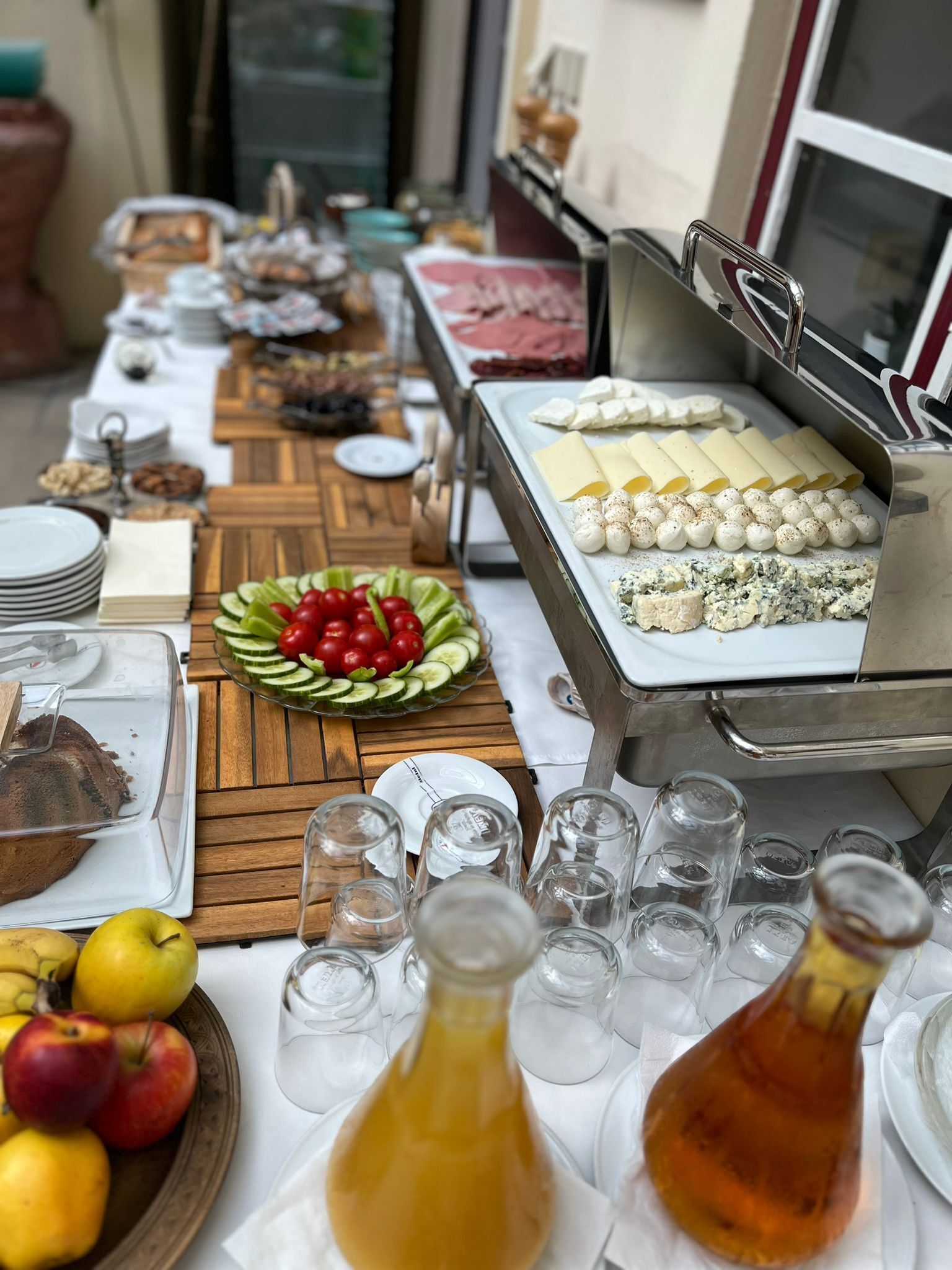 A buffet table with various food items including cheese, fruits, and a cake.