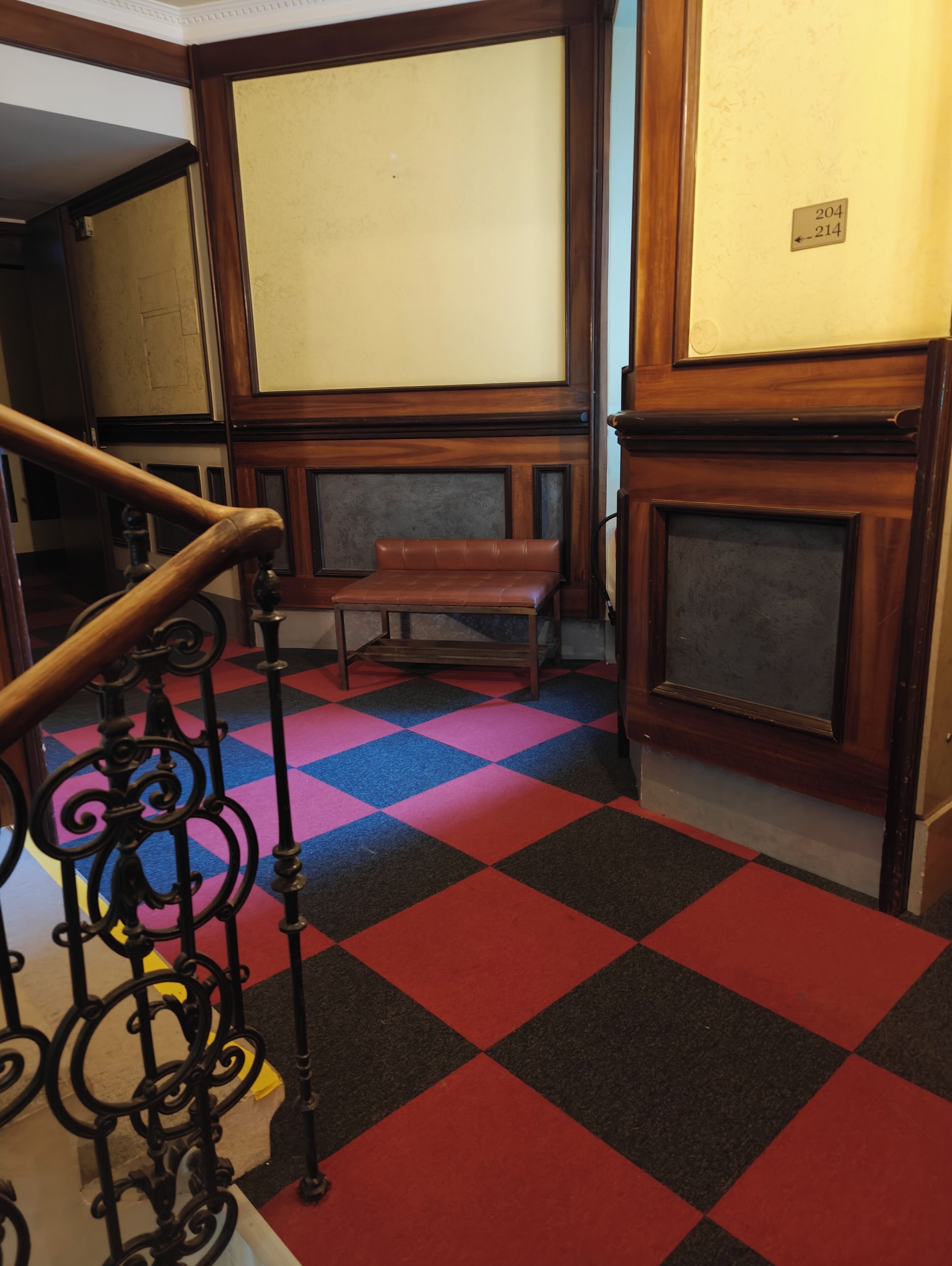 A staircase with a checkered floor, a bench, and a wooden wall with a door.