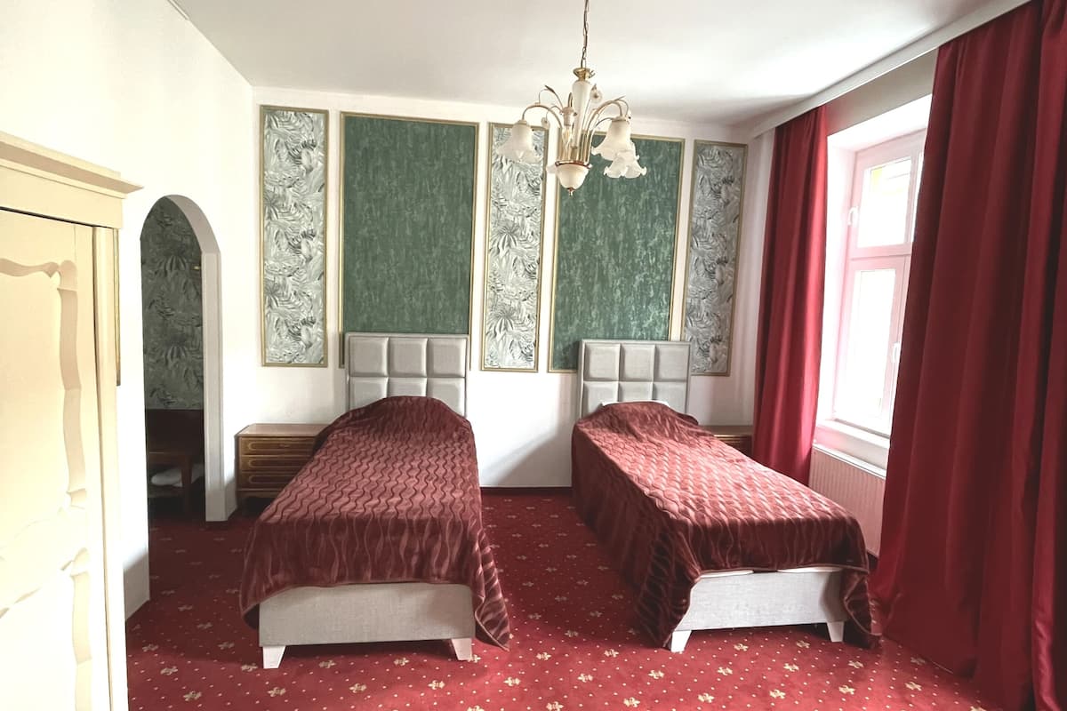 Ein Zimmer mit zwei Betten, einer Kandelaber und einem roten Teppich.