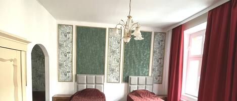 Habitación con dos camas, una araña y una alfombra roja.