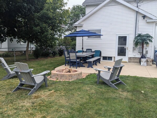 A backyard with a fire pit, outdoor furniture, and a patio table with chairs.