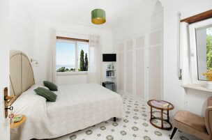 Ein Schlafzimmer mit einem Bett, einem kleinen Tisch, einem Stuhl, einem Fernseher und einem Fenster mit Blick.