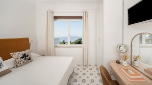 Une chambre d’hôtel comprenant un lit, un bureau, une chaise, une télévision, une fenêtre avec des rideaux et une vue sur l’extérieur.
