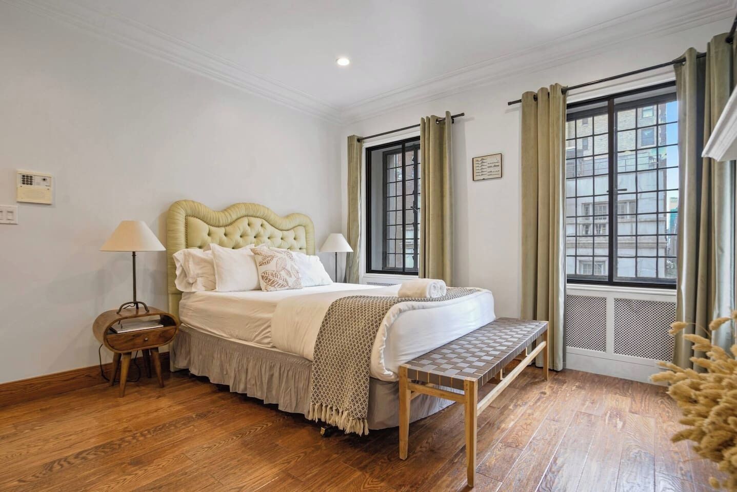 Una camera da letto con un letto grande, due comodini, una finestra con tende e un termosifone.