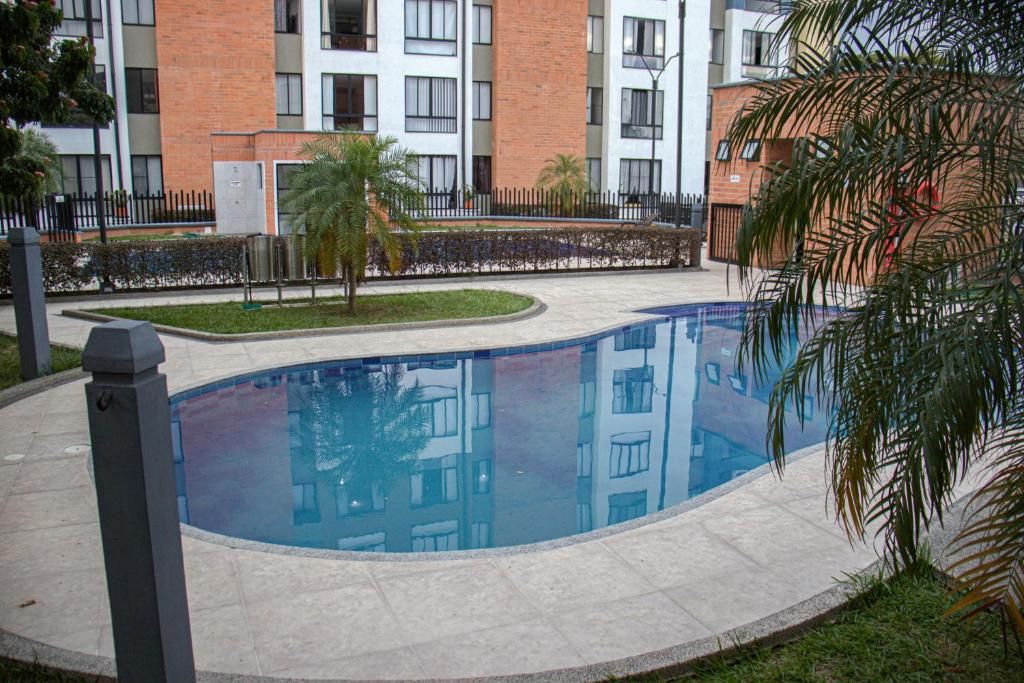 Une piscine entourée d’une zone pavée, avec un bâtiment en arrière-plan.