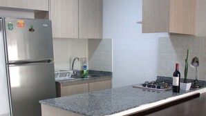 A modern kitchen with a stainless steel refrigerator, a granite countertop, a built-in stove, and a sink.