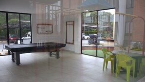 A spacious room with a billiards table, large windows, and a view of parked cars outside.
