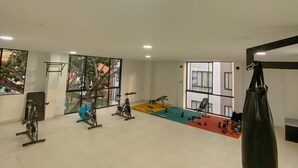 A gym with various exercise equipment, large windows, and a hanging punching bag.