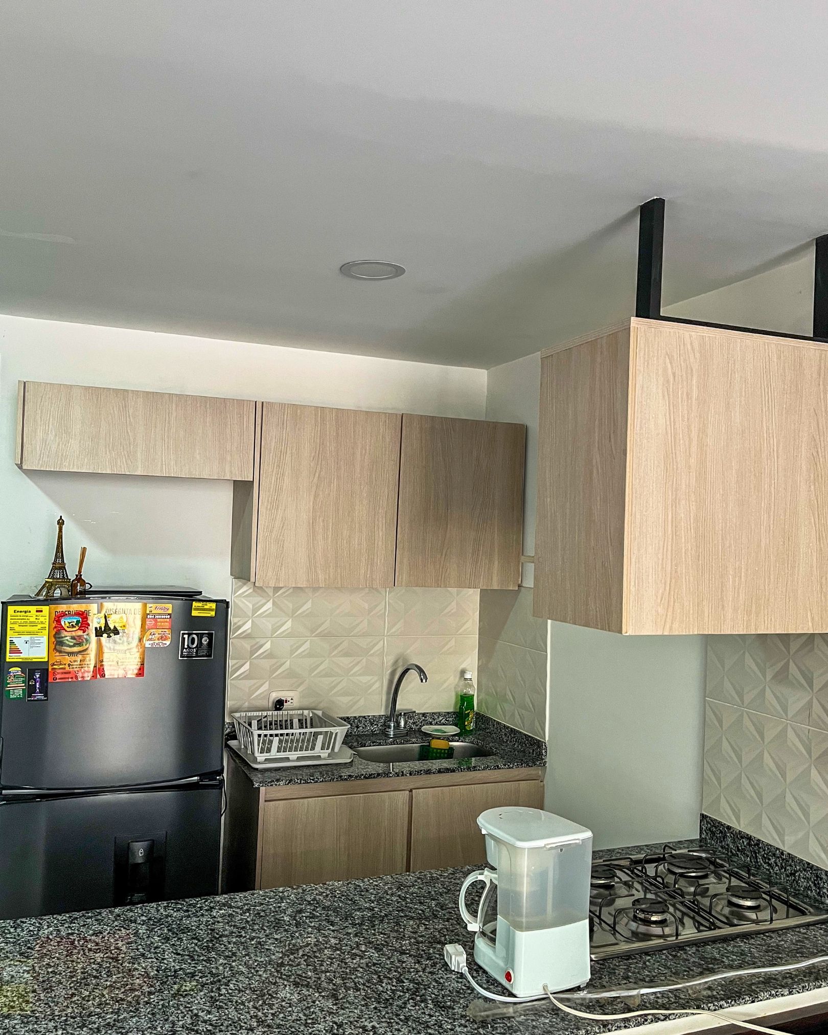 A kitchen with a refrigerator, a sink, a stove, and wooden cabinets.