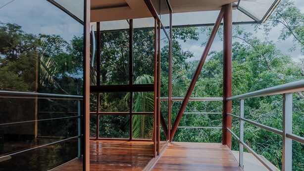 A modern interior with large glass windows, wooden flooring, and metal railings. - Piranha Eco-Lodge with Guided Tour (Cuyabeno)
