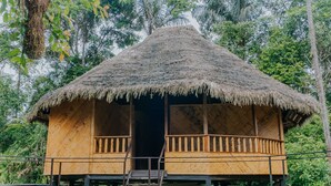 A thatched-roof wooden structure with a balcony, elevated on stilts, surrounded by lush greenery. - Piranha Eco-Lodge with Guided Tour (Cuyabeno)