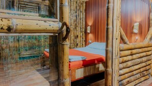 A room with a wooden bed, bamboo walls, and a window overlooking greenery. - Piranha Eco-Lodge with Guided Tour (Cuyabeno)