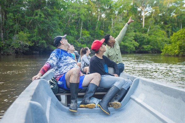 Een groep mensen in een boot op een rivier, omgeven door weelderige begroeiing.