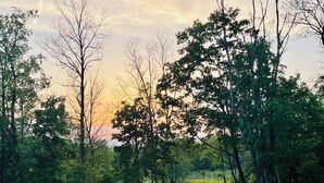 A scenic view from a balcony overlooking a lush landscape with a road and trees. - Peaceful space in the country. Deck&private indoor sauna. Surrounded by nature! (Horseheads)