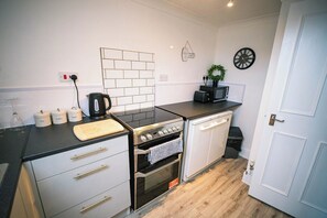 A modern kitchen with a gas stove, oven, and a microwave. There are cabinets, a countertop, and a door with a handle.