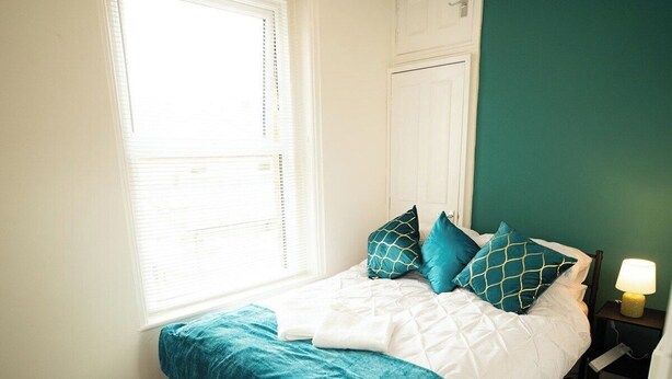 A bedroom with a bed, a nightstand, a lamp, a window, and a door. - 20%OFF|MonthlyEscape|Family|Leisure|WiFi|Sleeps4 (Suffolk)