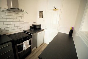 A compact kitchen with a stove, microwave, and a small dishwasher.