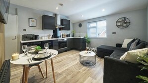A modern kitchen with built-in appliances, a dining area with a round table, and a living space with a sofa and a coffee table.