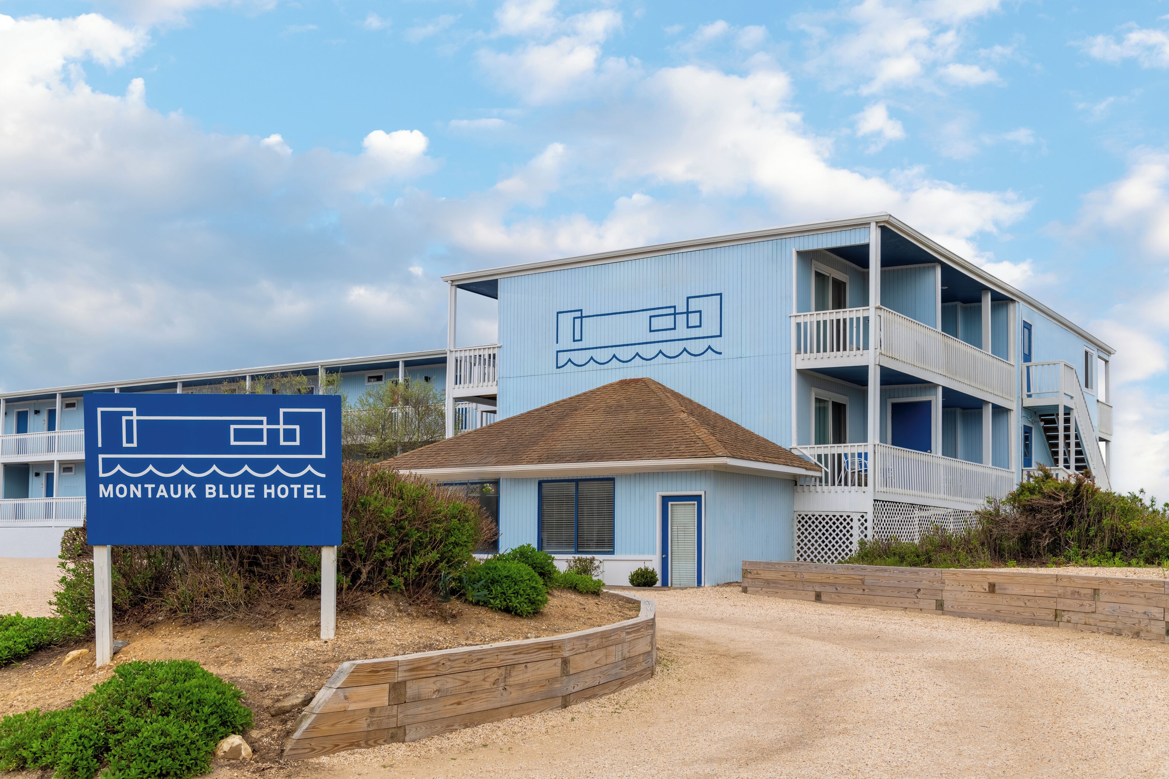 A two-story motel with a blue exterior and a sign indicating it is the Montauk Blue Hotel.