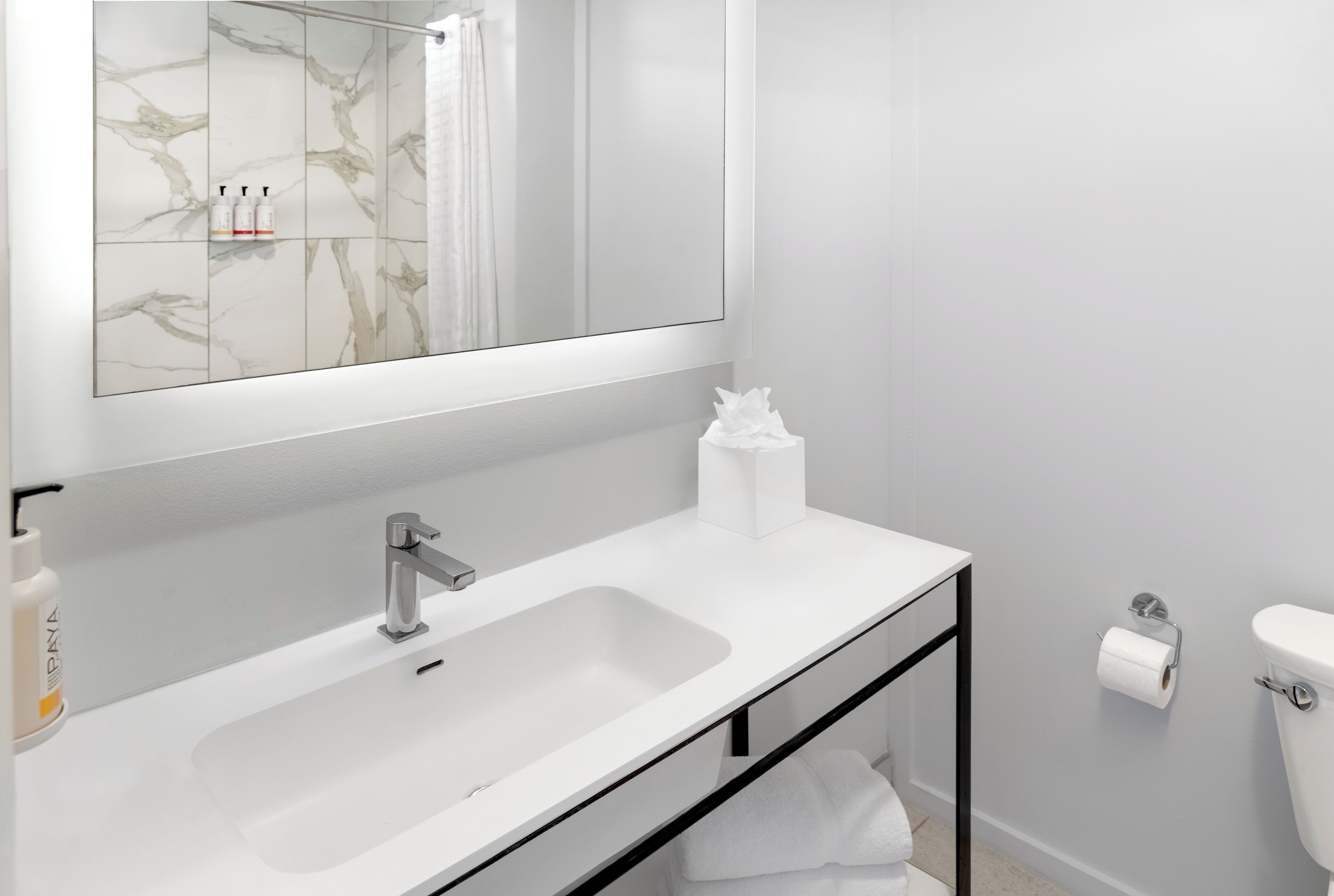Un baño moderno con un lavamanos blanco, un espejo grande y un inodoro.