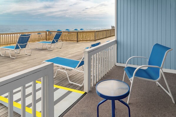 Une terrasse avec des chaises longues et une petite table, offrant une vue sur l’océan.