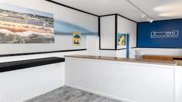 A reception area with a counter, a large beach-themed painting, and a blue wall with a nautical design.