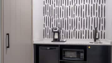 Una kitchenette compacta con microondas, cafetera y lavavajillas.