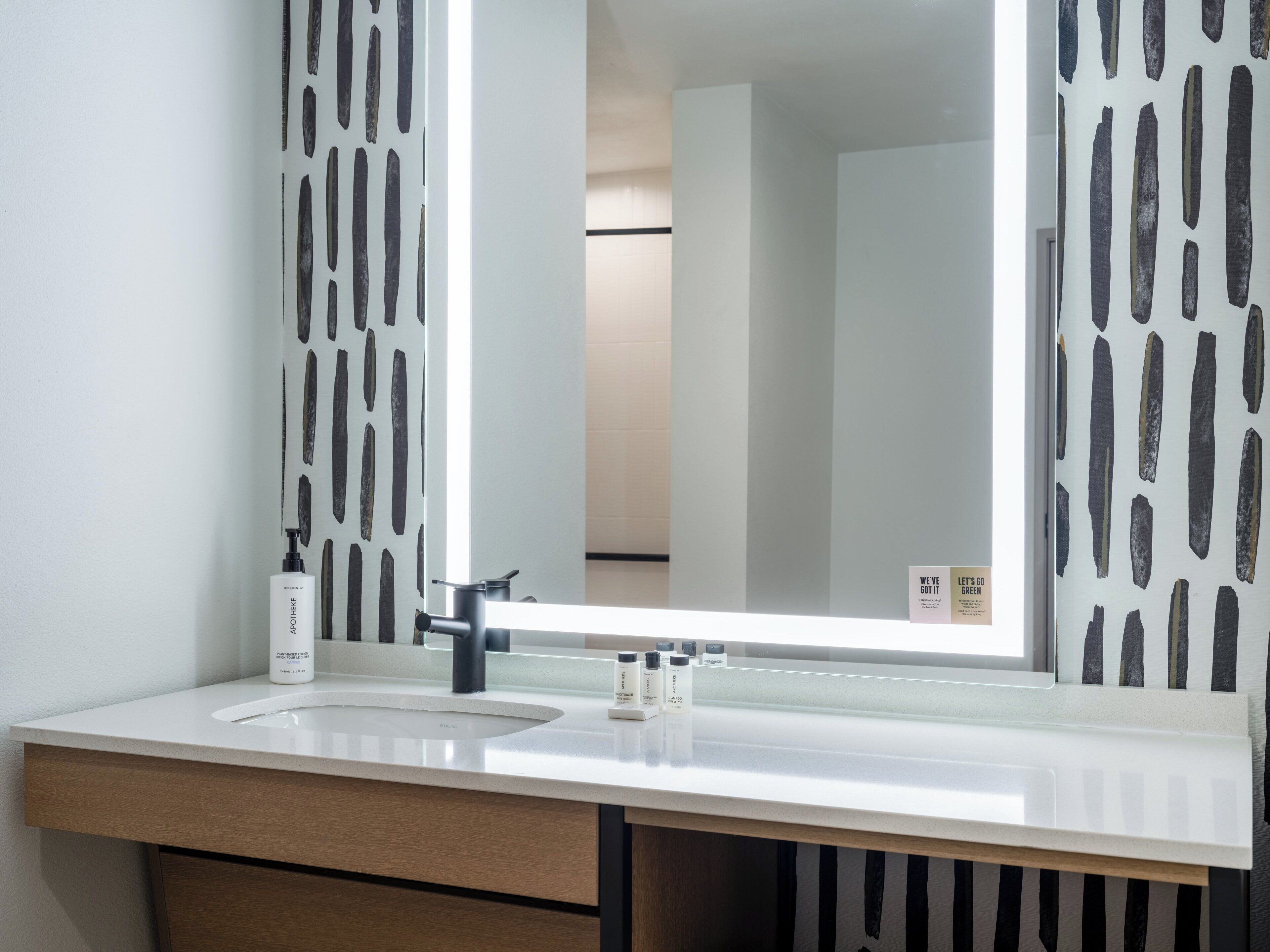 Un baño con un lavabo blanco, un espejo y un perchero para toallas.