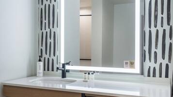 Un baño con un lavabo blanco, un espejo y un perchero para toallas.