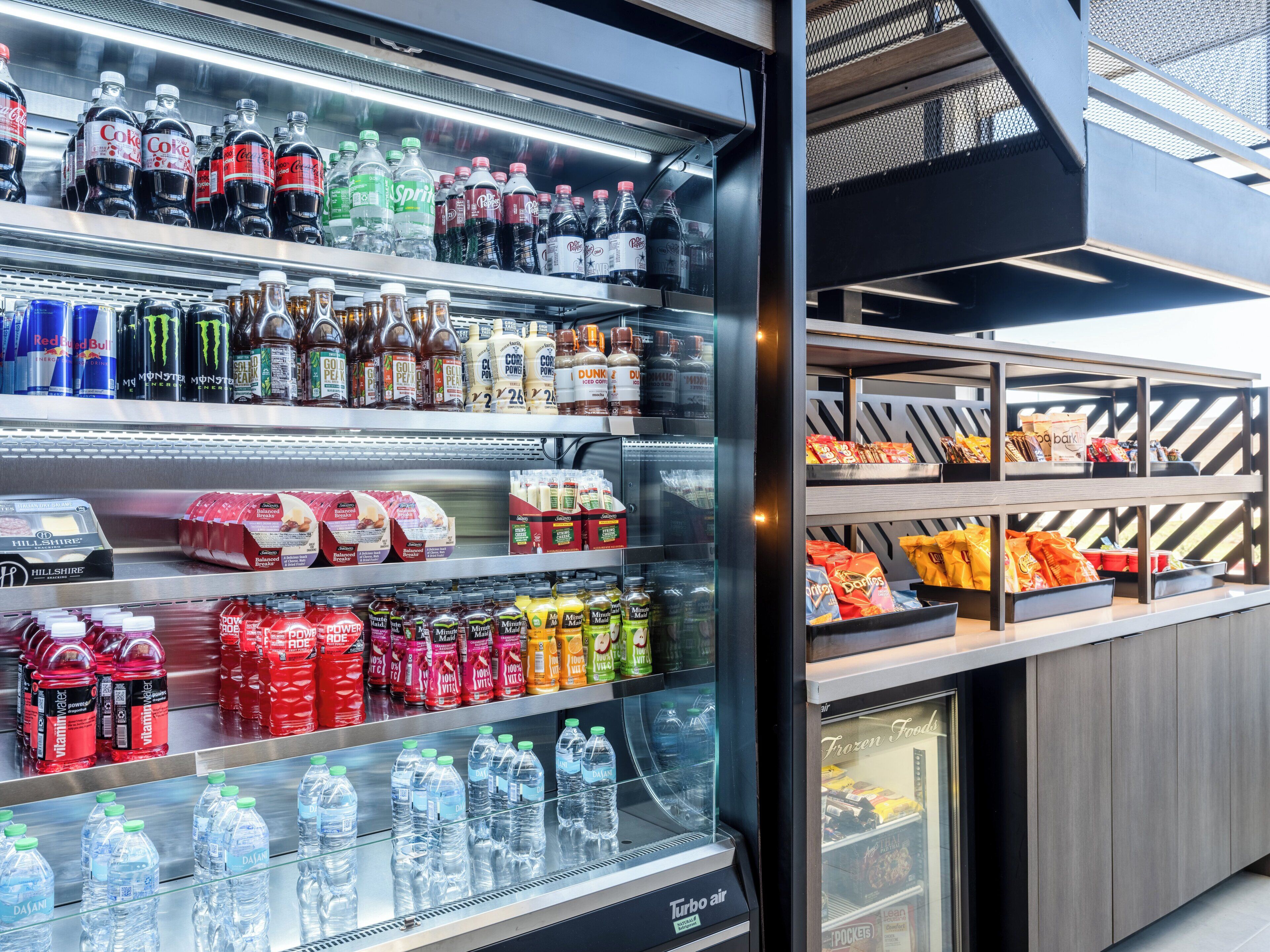 Máquina expendedora llena de diversas bebidas y aperitivos, incluyendo refrescos, bebidas energéticas y alimentos envasados.