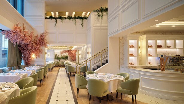 A spacious hotel lobby with a central staircase, multiple dining areas with green chairs and white tables, and a bakery counter. - InterContinental Presidente Monterrey by IHG (San Pedro Garza García)
