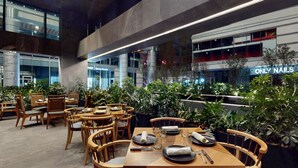 A modern indoor dining area with wooden tables and chairs, surrounded by potted plants. - InterContinental Presidente Monterrey by IHG (San Pedro Garza García)