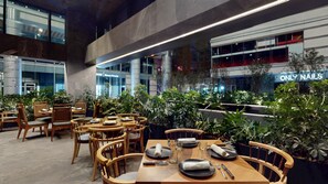 A modern indoor dining area with wooden tables and chairs, surrounded by potted plants. - InterContinental Presidente Monterrey by IHG (San Pedro Garza García)