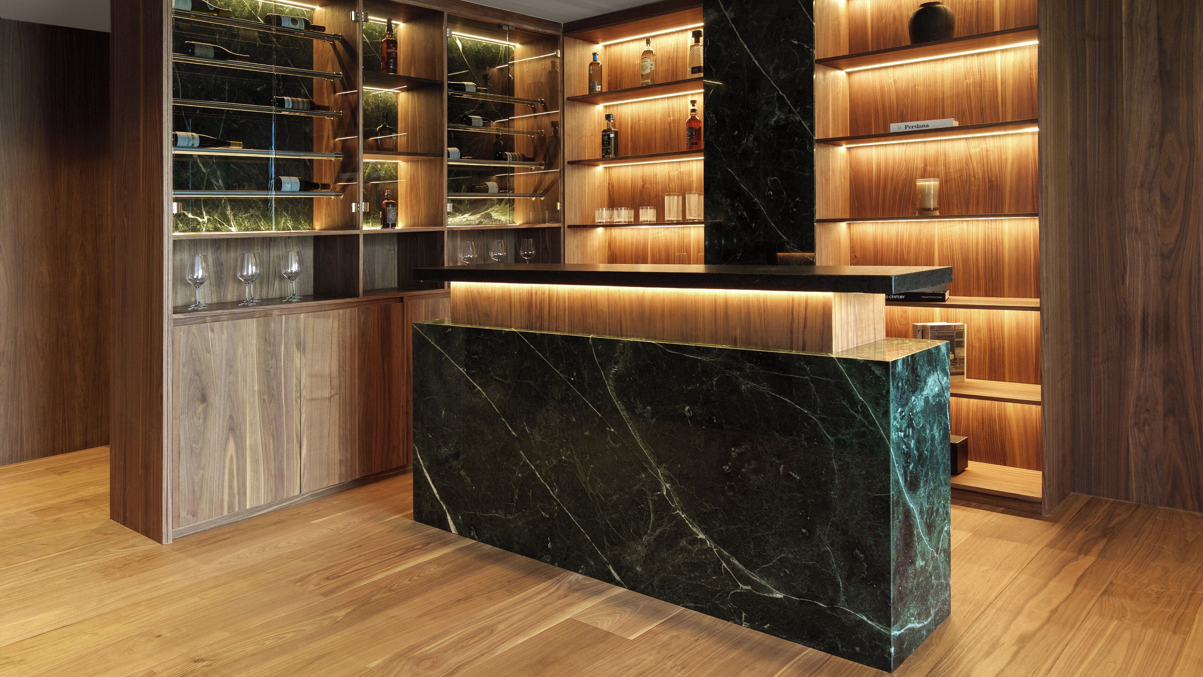 A modern kitchen with wooden cabinets, marble countertops, and a wine rack.