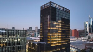 A modern high-rise building with a grid-like facade and illuminated windows, surrounded by other contemporary buildings in an urban setting. - InterContinental Presidente Monterrey by IHG (San Pedro Garza García)