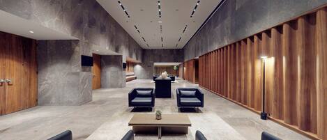 A modern lobby with a central seating area, a reception desk, and a wooden panel wall.