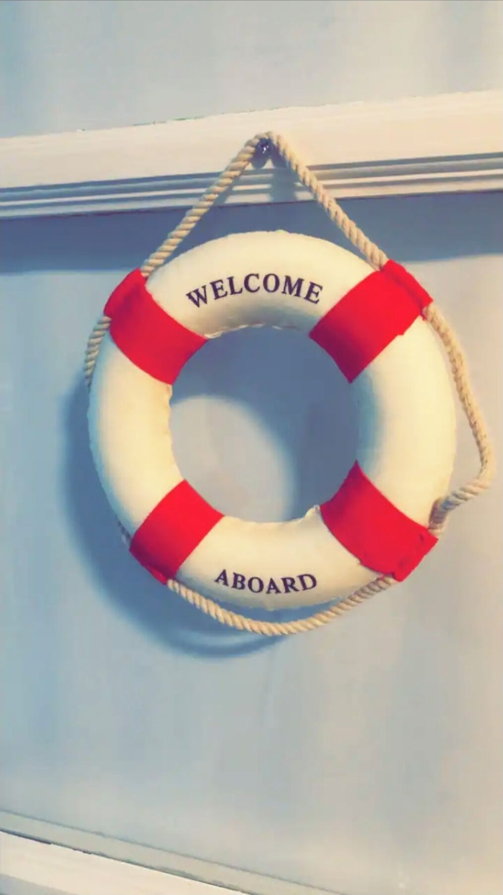 A life preserver with "WELCOME ABOARD" text hanging on a wall.