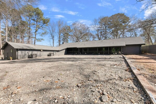 A building with a gravel driveway and a fenced area.