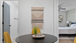 Een kamer met een ronde tafel, twee gele stoelen, een bed en een wanddecoratie.