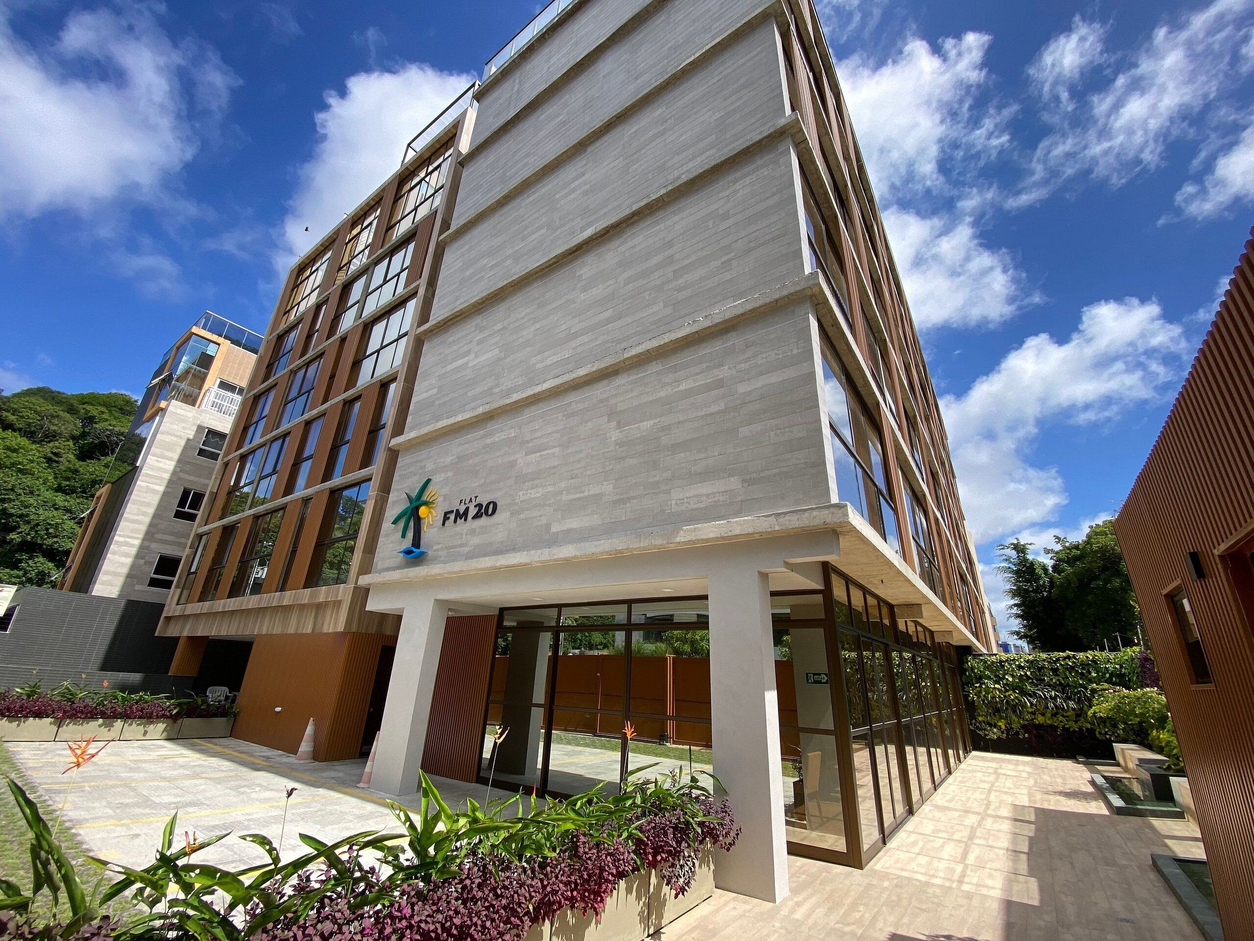 A modern building with a flat roof, large windows, and a sign reading "FLAT FM20".