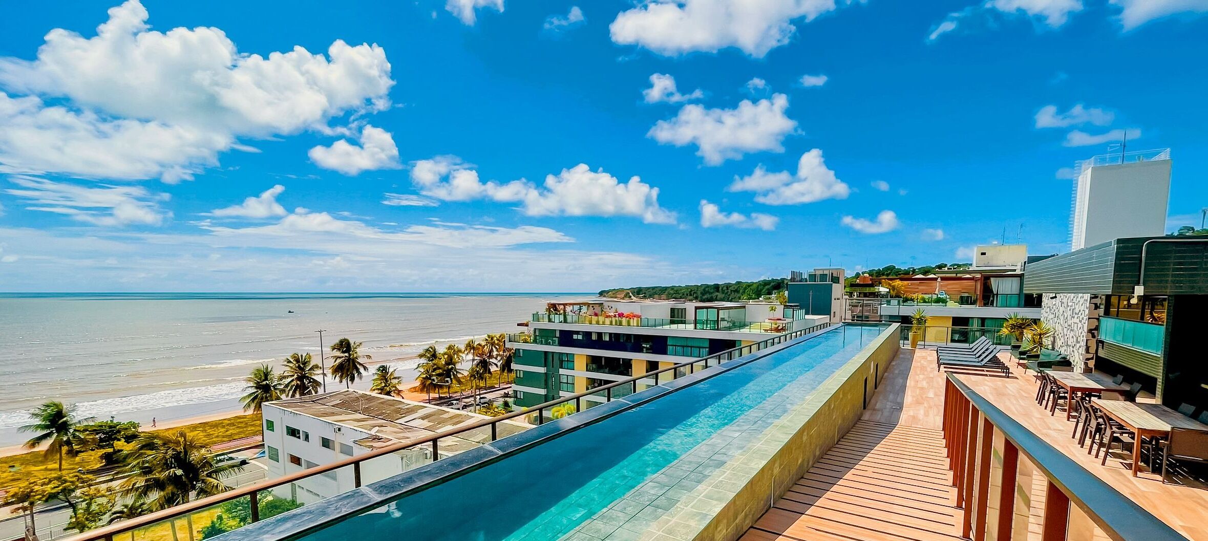 A hotel with a pool overlooking the beach, modern architecture, and a view of the ocean.
