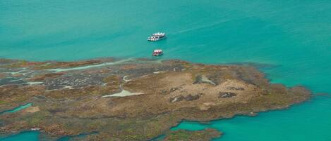 An aerial view of a coastal area with two boats and a rocky shoreline.