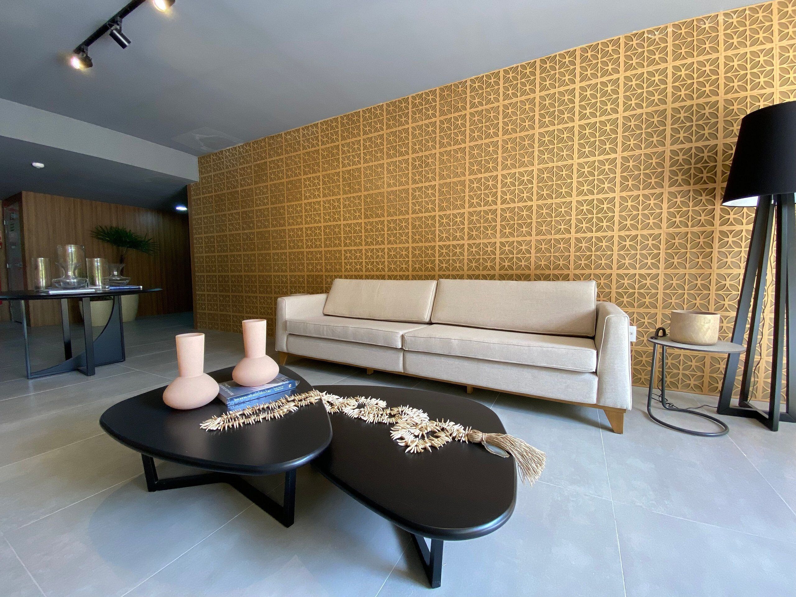 A modern living room with a patterned wall, a sofa, a coffee table, and a lamp.