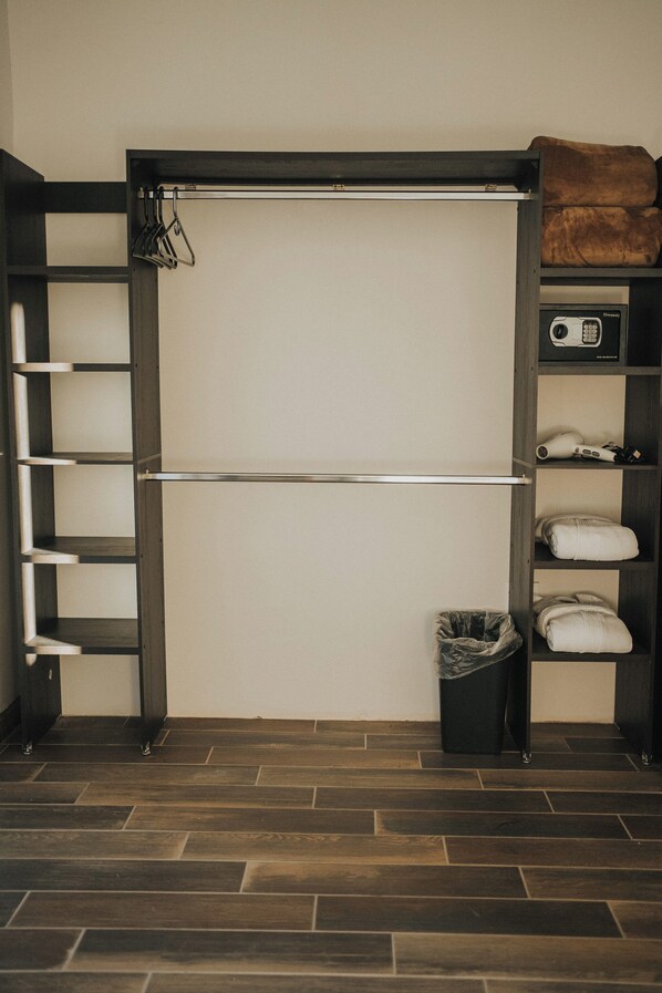 A room with a built-in closet featuring shelves, a hanging rod, and a folded blanket on top.