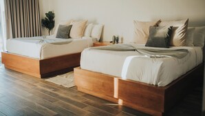 Una habitación de hotel moderna con dos camas, cabeceros de madera y un ventanal con cortinas.