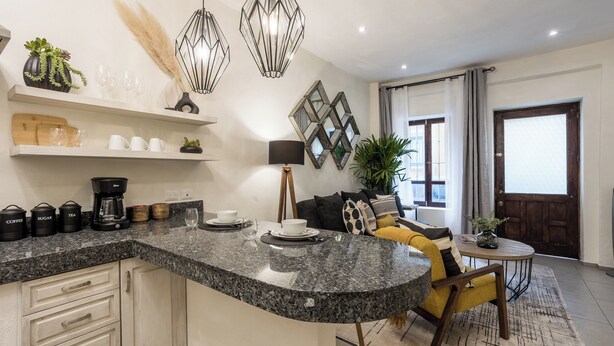 Una cocina moderna con encimeras de granito, armarios empotrados y un comedor con sofá amarillo y una mesa redonda pequeña.
