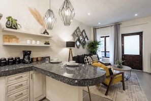 Une cuisine moderne dotée de plans de travail en granit, d’armoires intégrées et d’un coin repas avec un canapé jaune et une petite table ronde.
