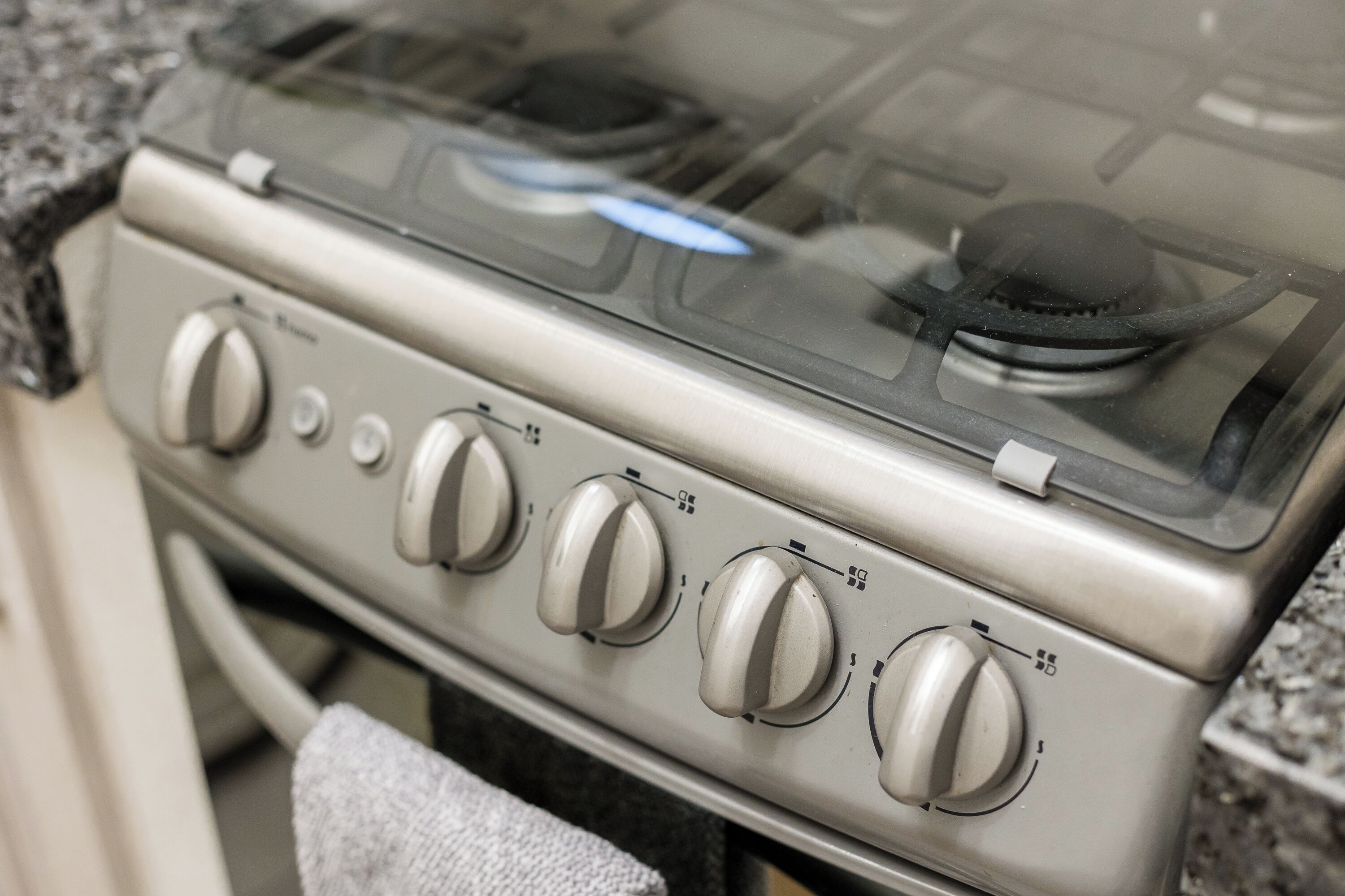 A kitchen with a stove, four knobs, and a glass top.