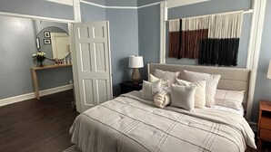 A bedroom with a large bed, a bedside table, a nightstand, a mirror, and a window with curtains. - ZO Family Cottage  (Mount Vernon)
