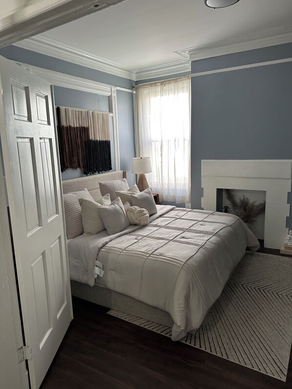 A bedroom with a bed, a bedside table, a lamp, a fireplace, and a window with curtains. - ZO Family Cottage (Mount Vernon)